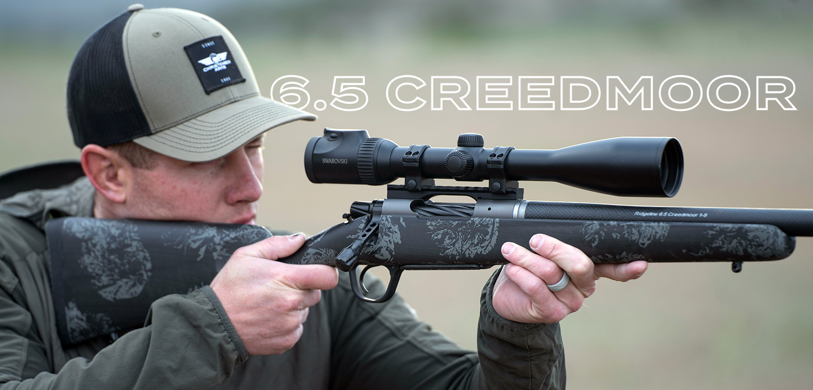 a man in a Christensen Arms hat holding a Ridgeline FFT rifle chambered in 6.5 Creedmoor