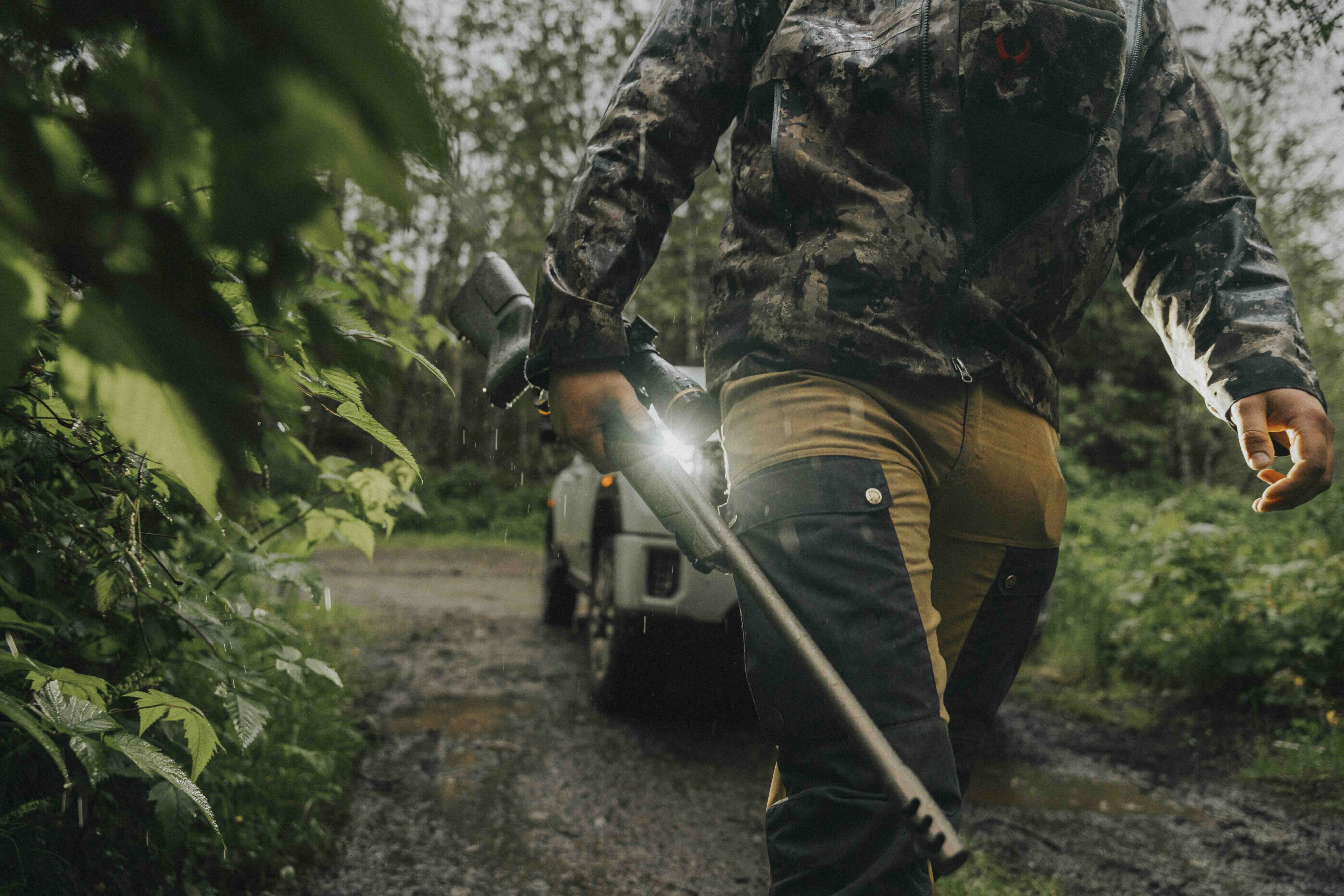 Hunter carrying a Christensen Arms Evoke hunting rifle in wet forest conditions