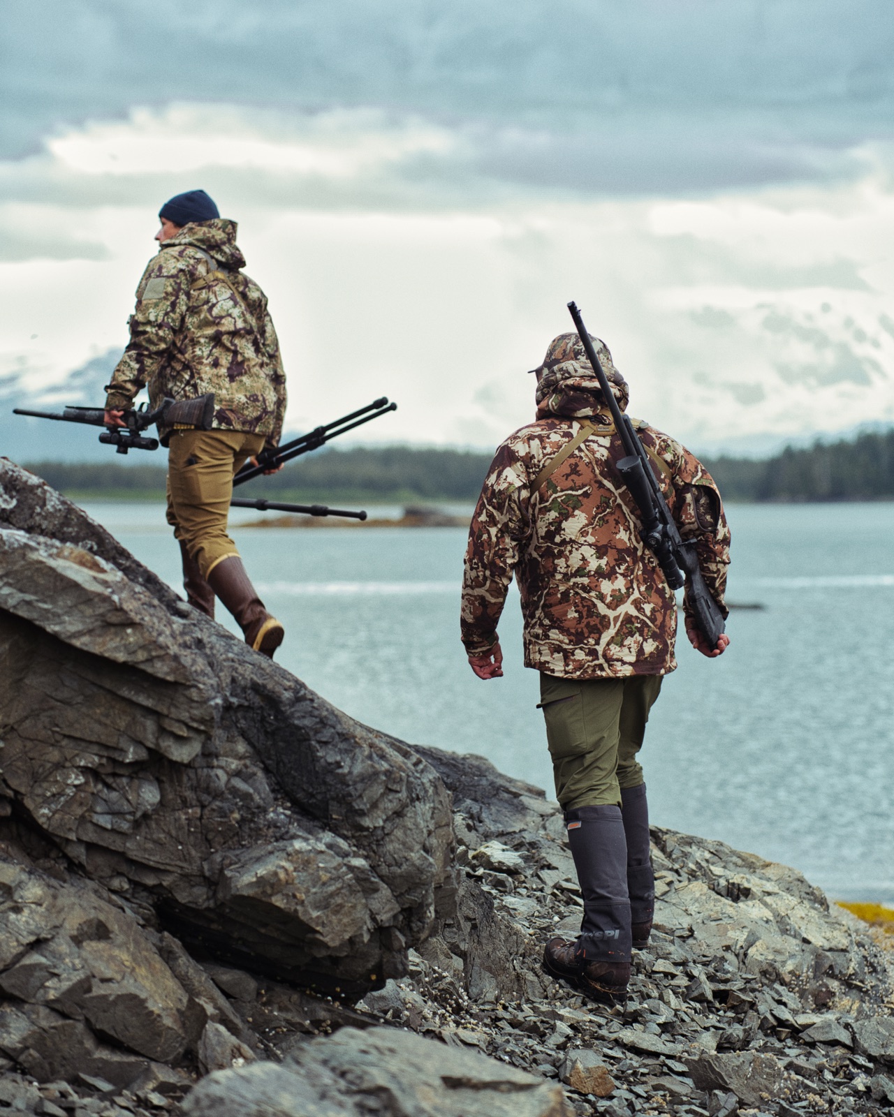 Hunters carrying lightweight rifles across rocky backcountry terrain