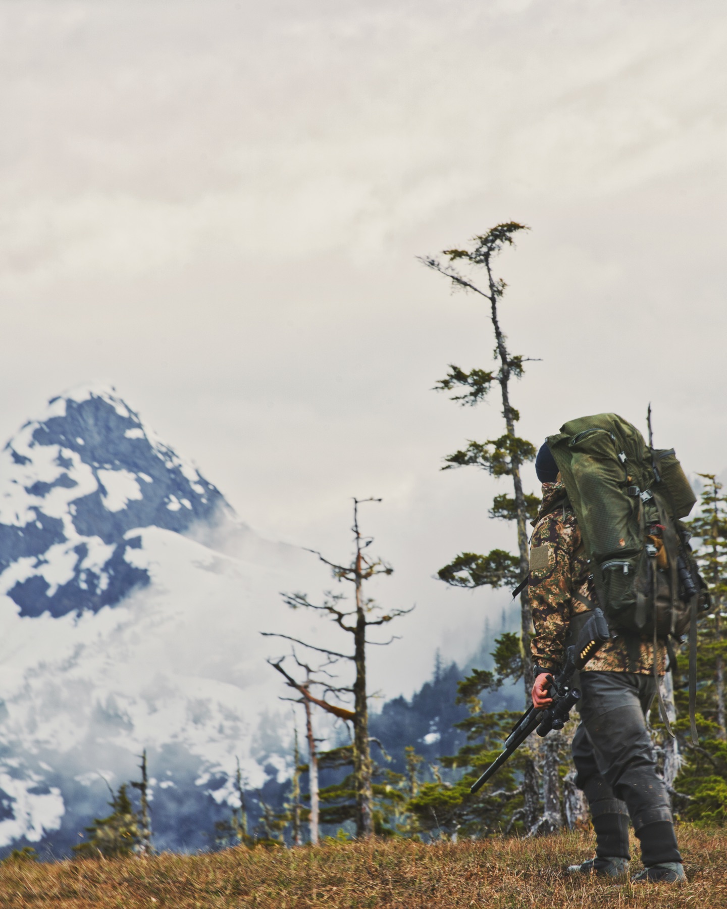 Backcountry hunter carrying a lightweight rifle in mountain terrain