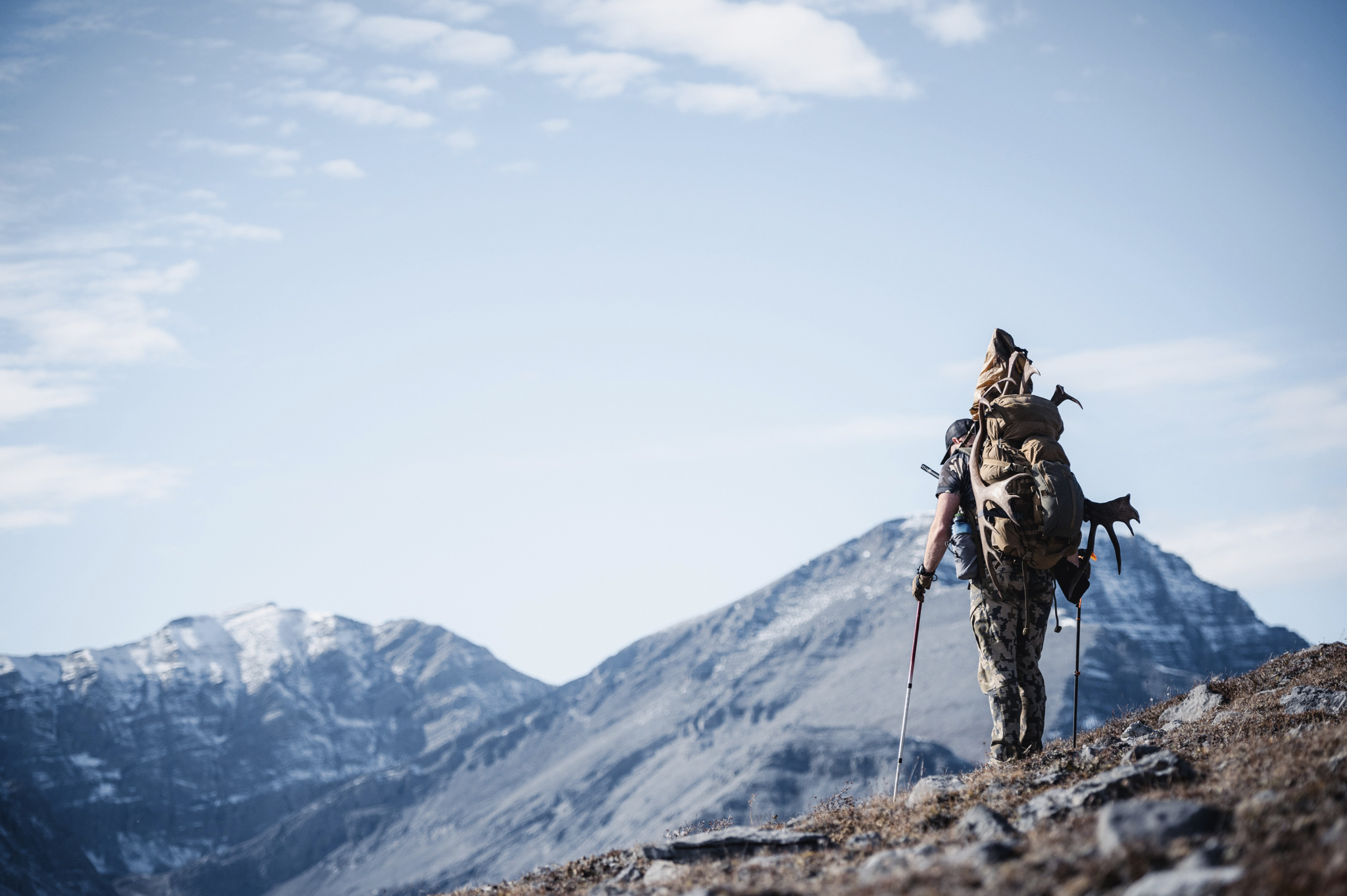 Hunter carrying a lightweight rifle for Western hunting through mountain terrain