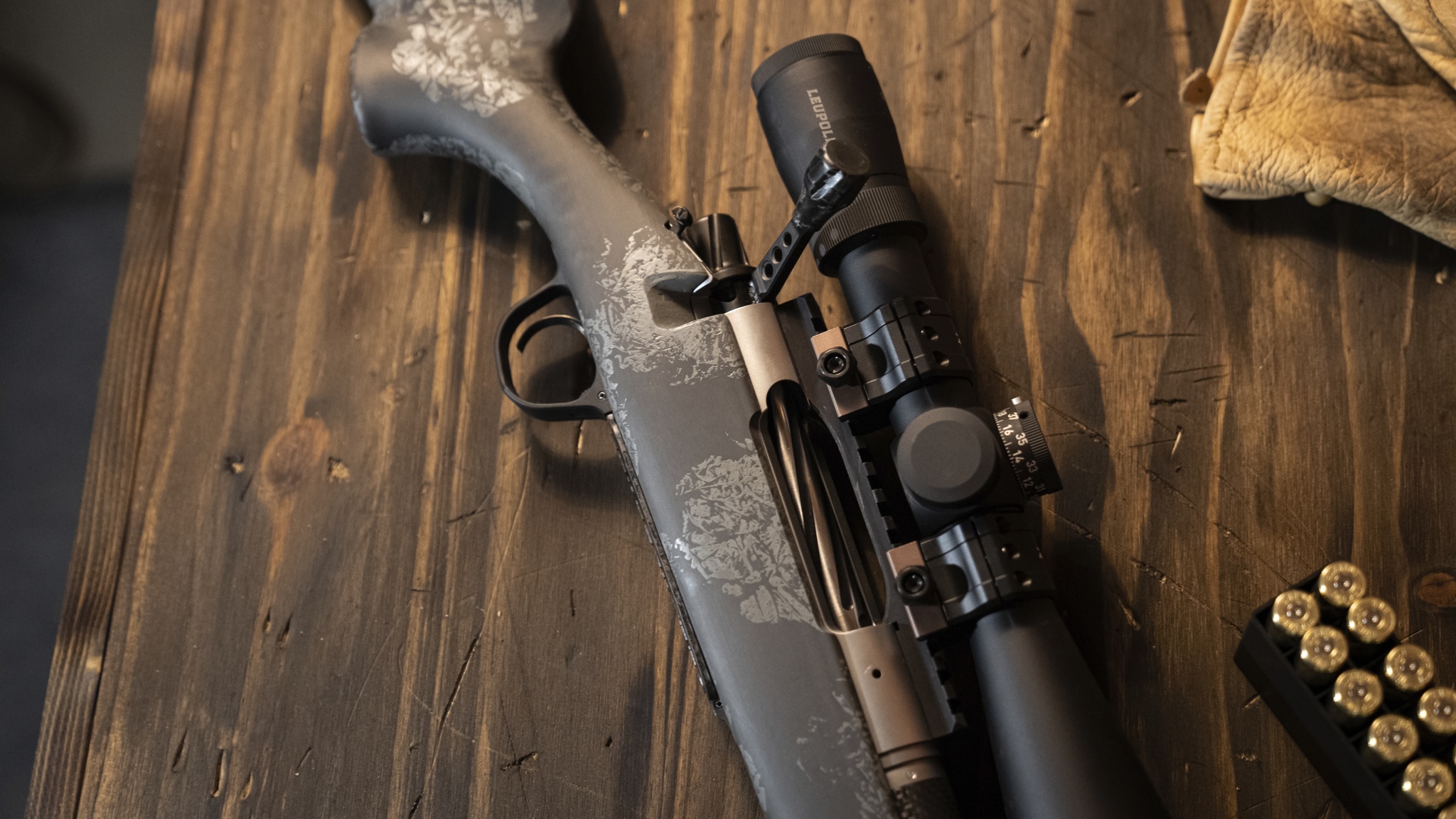 Scoped rifle action resting on a wooden workbench